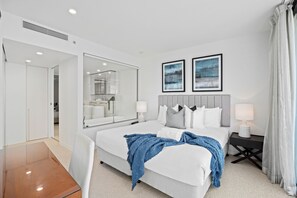 A modern hotel room with a large bed, a bedside table, a mirror, and two framed pictures on the wall.