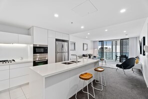 A modern kitchen with a central island, built-in appliances, and a view to a balcony.