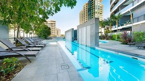 A swimming pool with lounge chairs and a clear view of surrounding buildings. - Oracle Resort 2 Bedroom Premium City Hosted by Gold Coast Luxury Resorts (Broadbeach)