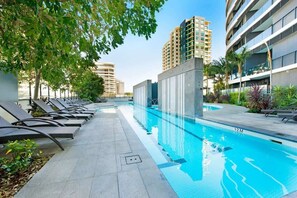 Une piscine dotée de chaises longues et offrant une vue dégagée sur les bâtiments environnants.