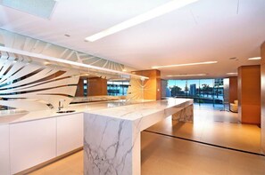 Une cuisine moderne dotée d’un plan de travail en marbre, d’un pare-feu en verre et offrant une vue sur le paysage urbain.