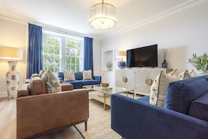 A living room with a sofa, armchair, coffee table, and TV. - Skye Sands | Westview House | St Andrews (St Andrews)
