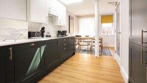 Una cocina moderna con armarios oscuros, una encimera blanca y un tragaluz.