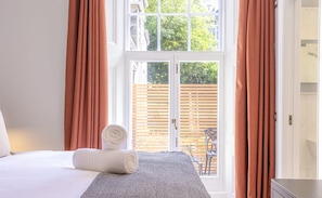 Ein Hotelzimmer mit einem Bett, einem Vorhangfenster, einem Handtuch und Blick auf einen Holzzaun.