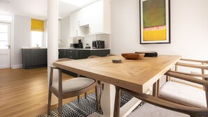 Una cocina moderna con armarios oscuros, una mesa de comedor de madera y un cuadro abstracto enmarcado en la pared.