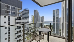 Enjoy the ocean view from this balcony with a round table and two chairs.