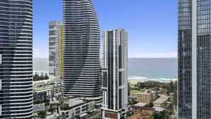 Stunning cityscape with a curved skyscraper and adjacent glass tower, set against a clear blue sky and ocean backdrop.
