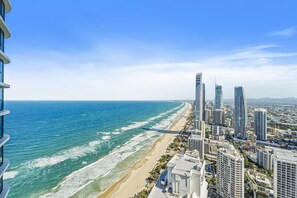 A coastal cityscape with high-rise buildings, a beach, and a clear sky.