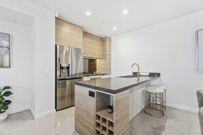 Een moderne keuken met een roestvrijstalen koelkast, een inbouwoven en een houten keukeneiland met barstoelen.