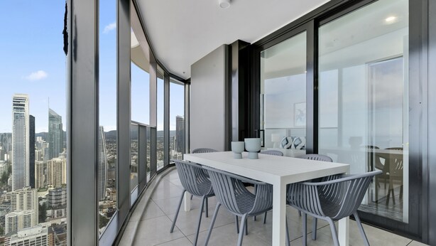 Varanda moderna com mesa e cadeiras brancas, com vista para a cidade.