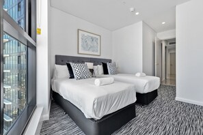 A hotel room with two beds, a large window, and a view of the city.