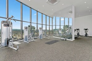 A gym with various exercise equipment, large windows, and a city view.