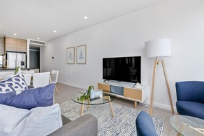 A modern living room with a sofa, a coffee table, a TV, and a lamp.