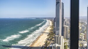 Paisagem costeira com edifícios altos, uma praia e céu claro.