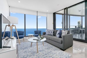 A modern living room with a large window, a sofa, two armchairs, a coffee table, and a floor lamp.