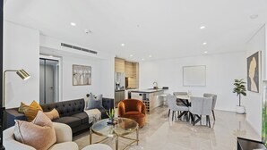 Um espaço de estar moderno com sofá, poltrona, mesa de jantar e cozinha.