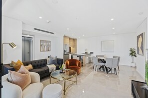 Een moderne leefruimte met een bank, fauteuil, eettafel en keukenhoek.