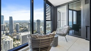 Um apartamento alto com varanda, janelas amplas e vista para a cidade.