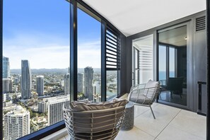 Een hoog appartementencomplex met balkon, grote ramen en uitzicht op de stad.