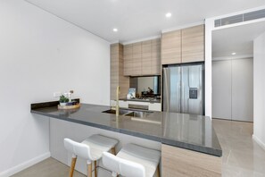 Une cuisine moderne dotée d’un îlot central, de tabourets de bar, d’un réfrigérateur et d’une cuisinière.