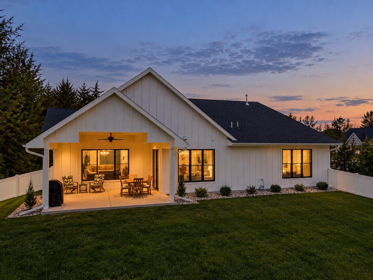 A modern two-story house with a covered patio, a fireplace, and a large window.