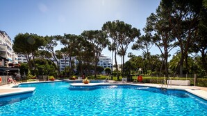 Una gran piscina al aire libre rodeada de árboles y un edificio.