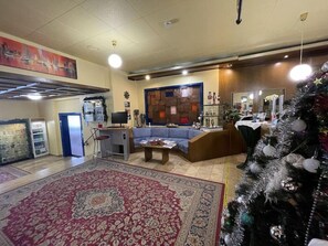 Uma sala de estar com um sofá, uma mesa de centro, uma televisão e um pinheiro de Natal.