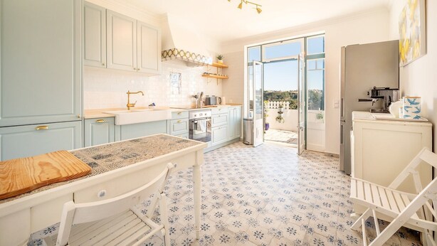A kitchen with light blue cabinets, a white countertop, and a patterned floor. - Lovely countryside house near the beach (Carvoeira)