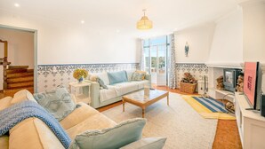 A spacious living room with a sofa, coffee table, and a fireplace. - Lovely countryside house near the beach (Carvoeira)