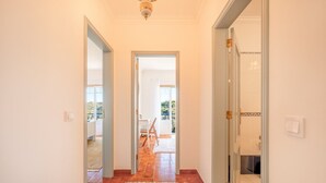 A hallway with a wooden floor, a rug, and a view of an outdoor area with a table and chairs. - Lovely countryside house near the beach (Carvoeira)