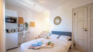 Ein Hotelzimmer mit einem Bett, einem Schreibtisch mit einer Mikrowelle, einem Stuhl und einer Treppe, die in ein weiteres Zimmer führt.