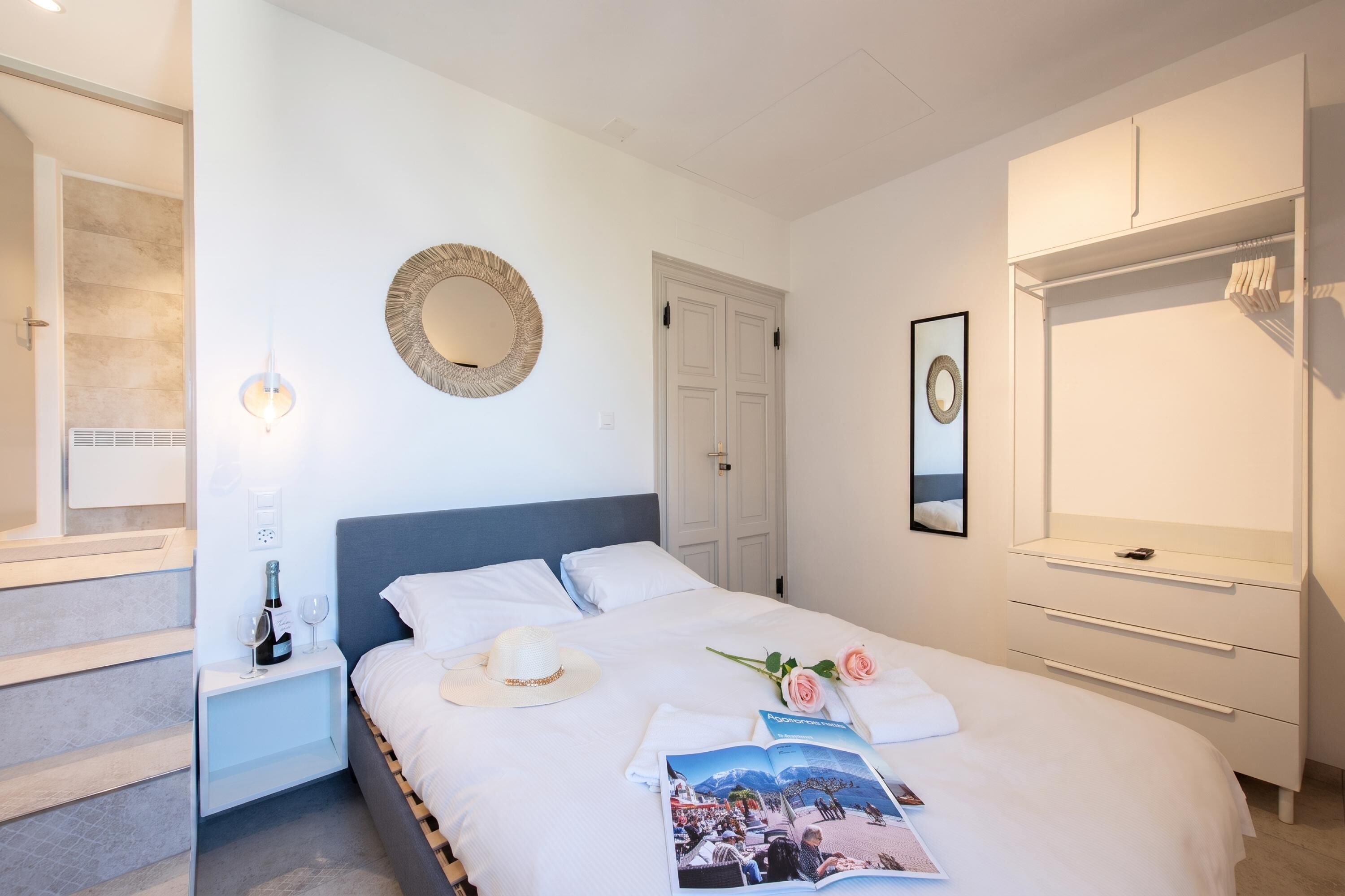 Hotellihuone, jossa on sänky, yöpöytä, yölamppu ja vaatekaappi.