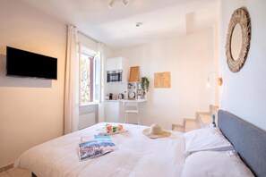Habitació d'hotel amb un llit, televisió de pantalla plana, escriptori amb microones, una cadira i una escala.