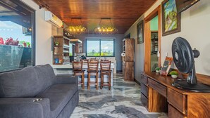 Eine moderne Küche mit Marmorboden, Holzschränken und einem Essbereich mit grauem Sofa und Holzstühlen.