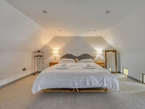 Ein Schlafzimmer mit einem Bett, Nachttischlampen, einem Spiegel und einer Pendelleuchte.