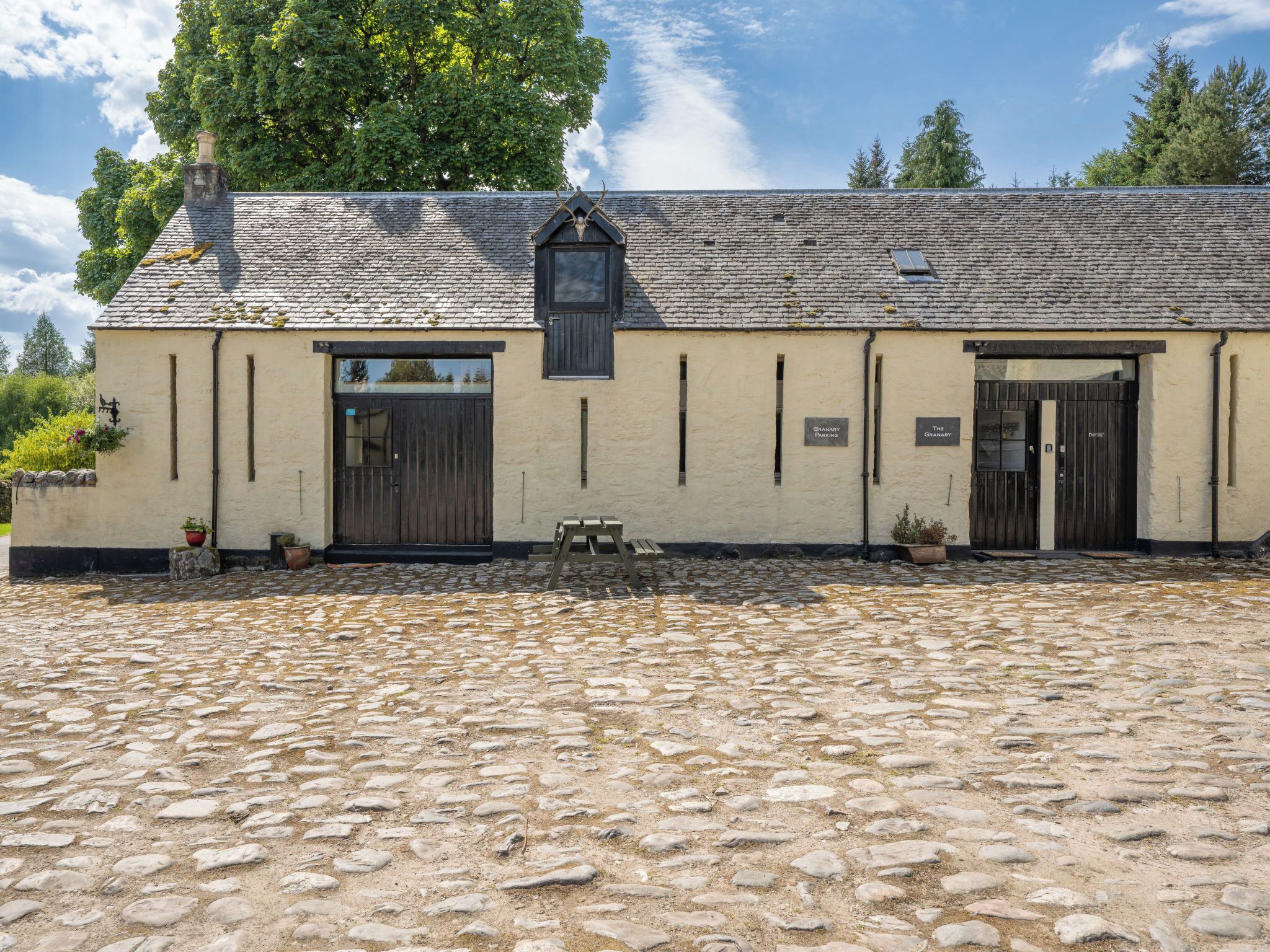 A building with a stone roof, two doors, and a bench in front.