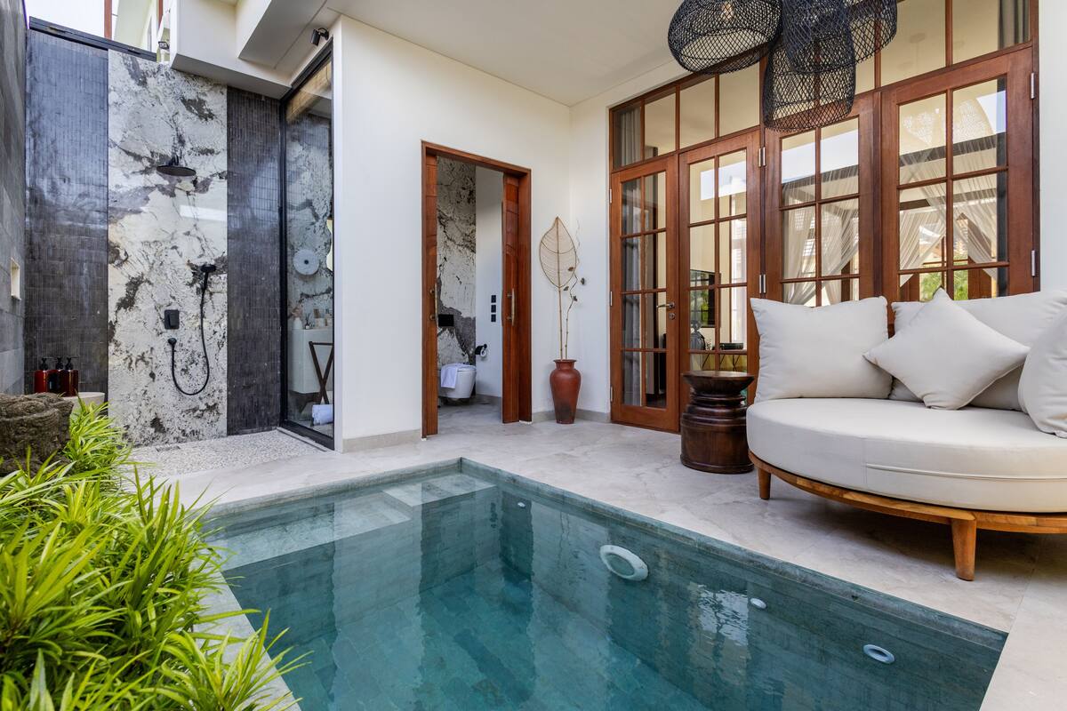 A pool area with a spa, a sofa, and a large window.