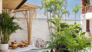 A tropical outdoor area with a pool, wooden furniture, and lush greenery. - Plawa Laguna Bali (Pererenan)