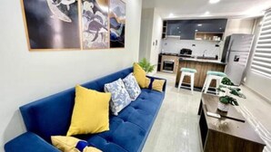 Un salon moderne avec un canapé bleu, une table basse en bois et des œuvres d’art abstraites accrochées au mur.