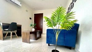 Un salon avec un canapé bleu, une table basse en bois, une chaise noire et une plante en pot.