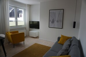 A living room with a sofa, a yellow armchair, a TV, and a framed picture on the wall. - Apartment 'Muggelbude' with Mountain View, Shared Garden and Wi-Fi (Braunlage)