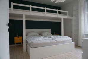 A bunk bed with a white frame, a bedside table with a lamp, and a window with curtains. - Apartment 'Muggelbude' with Mountain View, Shared Garden and Wi-Fi (Braunlage)