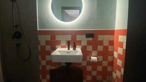 Een badkamer met een wastafel, spiegel en douche.