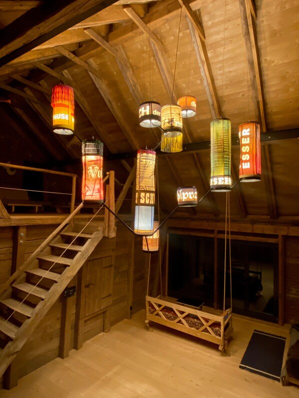 Un intérieur en bois avec un escalier, des lanternes suspendues et une fenêtre.