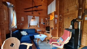 Ein gemütliches Blockhaus-Interieur mit einem blauen Sofa, einem Schaukelstuhl, einem kleinen Tisch und einem Kamin.
