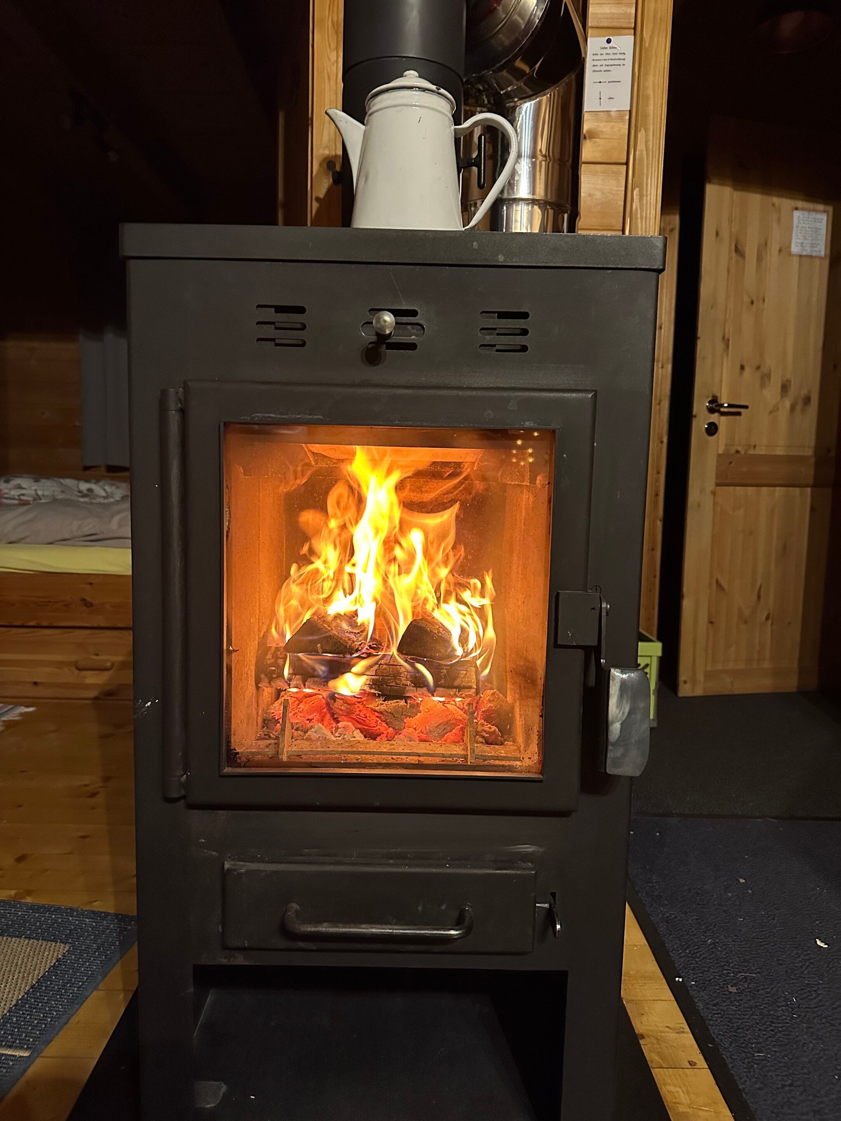 Ein Kaminofen mit Glasfront, einem Griff und einer Bedienkonsole.