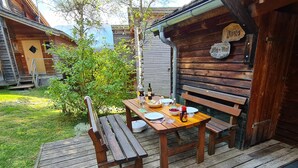 Eine Holzdielen-Terrasse mit Essbereich, umgeben von Holzhütten.