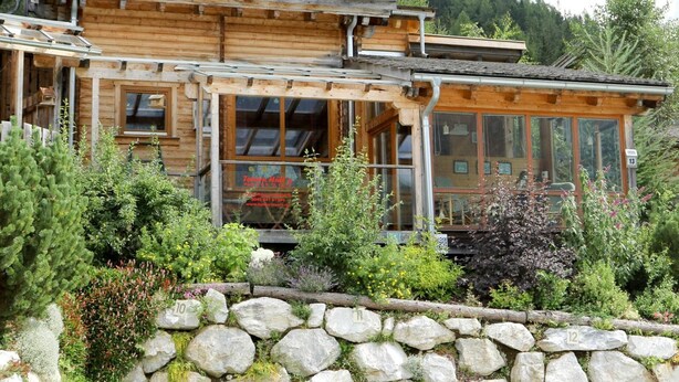 Eine Holzhütte mit Steinwand, Glastür und Bergblick.