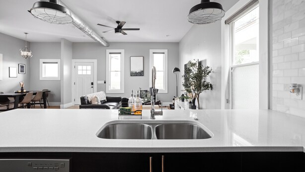 Een moderne keuken met een groot kookeiland, roestvrijstalen apparatuur en hanglampen.