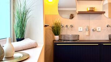A modern bathroom with a vanity, a mirror, and a potted plant.